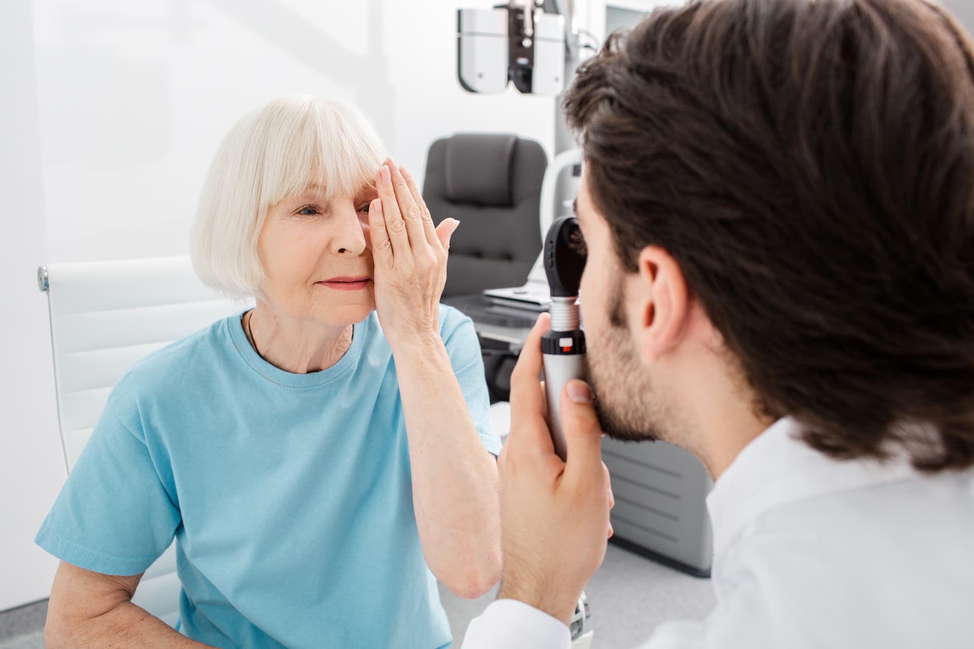 elderly woman getting a cataract test by doctor observing eye movement of just one eye